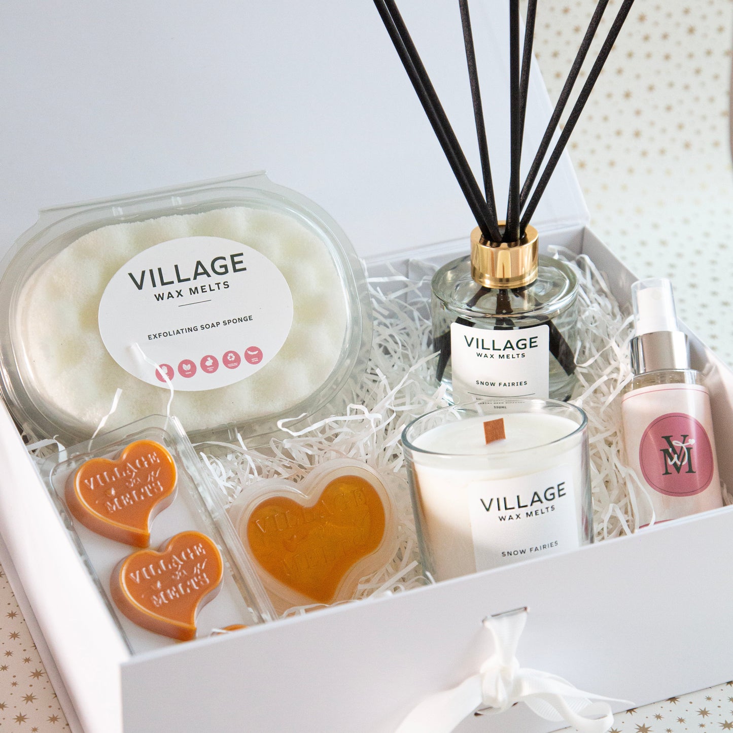 Gift set with Village products including candles, diffuser, and soap on a white background