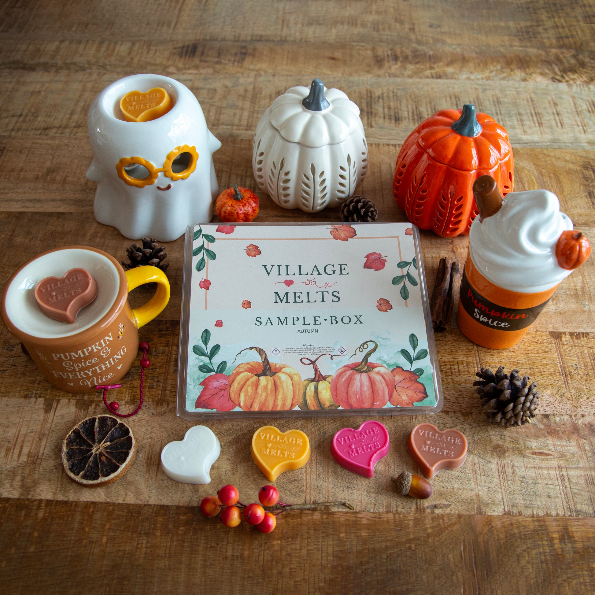 Collection of Halloween-themed wax melts and containers on a wooden surface with a 'Village Melts' sample box.